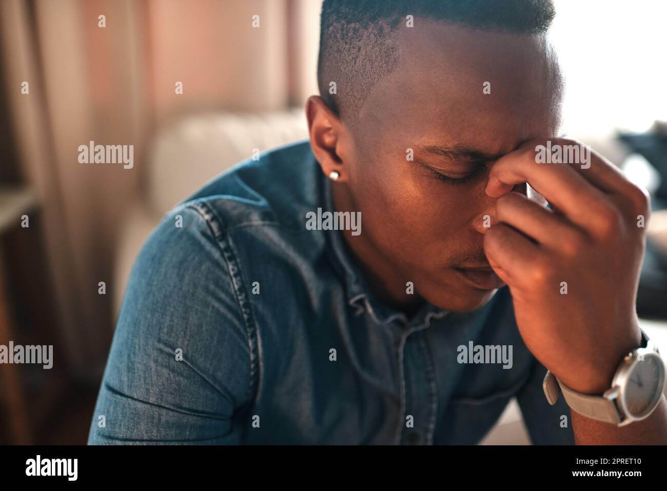 Stressed, tired businessman with headache alone at home. Man having eye tension or strain from overworking, burnout and anxiety. Depressed male having problems at work, suffering from lack of sleep. Stock Photo