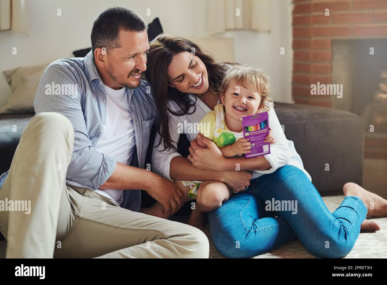 Growing up, children need love and affection. a young mother and father spending time with their adorable little daughter in the living room at home. Stock Photo