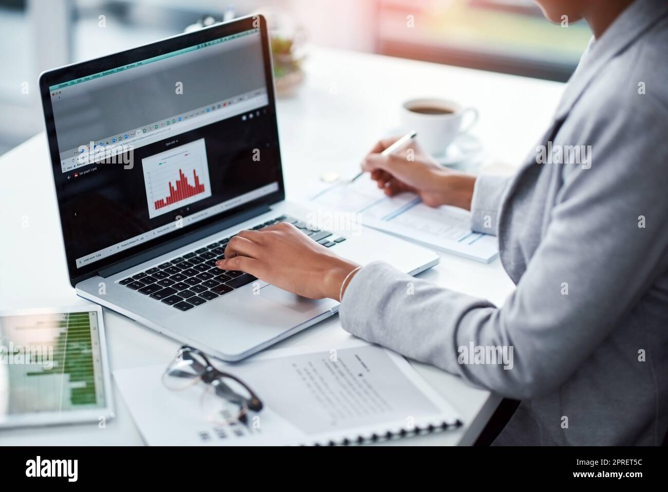 Female project manager typing on laptop looking at charts, analyzing statistics. Financial data analyst or business woman looking at KPI bar graph, measuring company strategy success and performance. Stock Photo