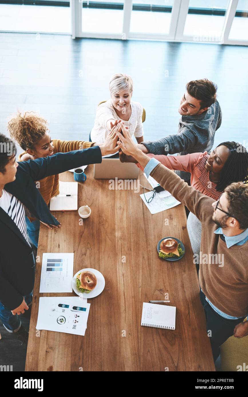Diverse group of businesspeople high five after planning a meeting in an office. Above ambitious happy confident professional team of colleagues celebrating a success, achievement and feeling excited Stock Photo