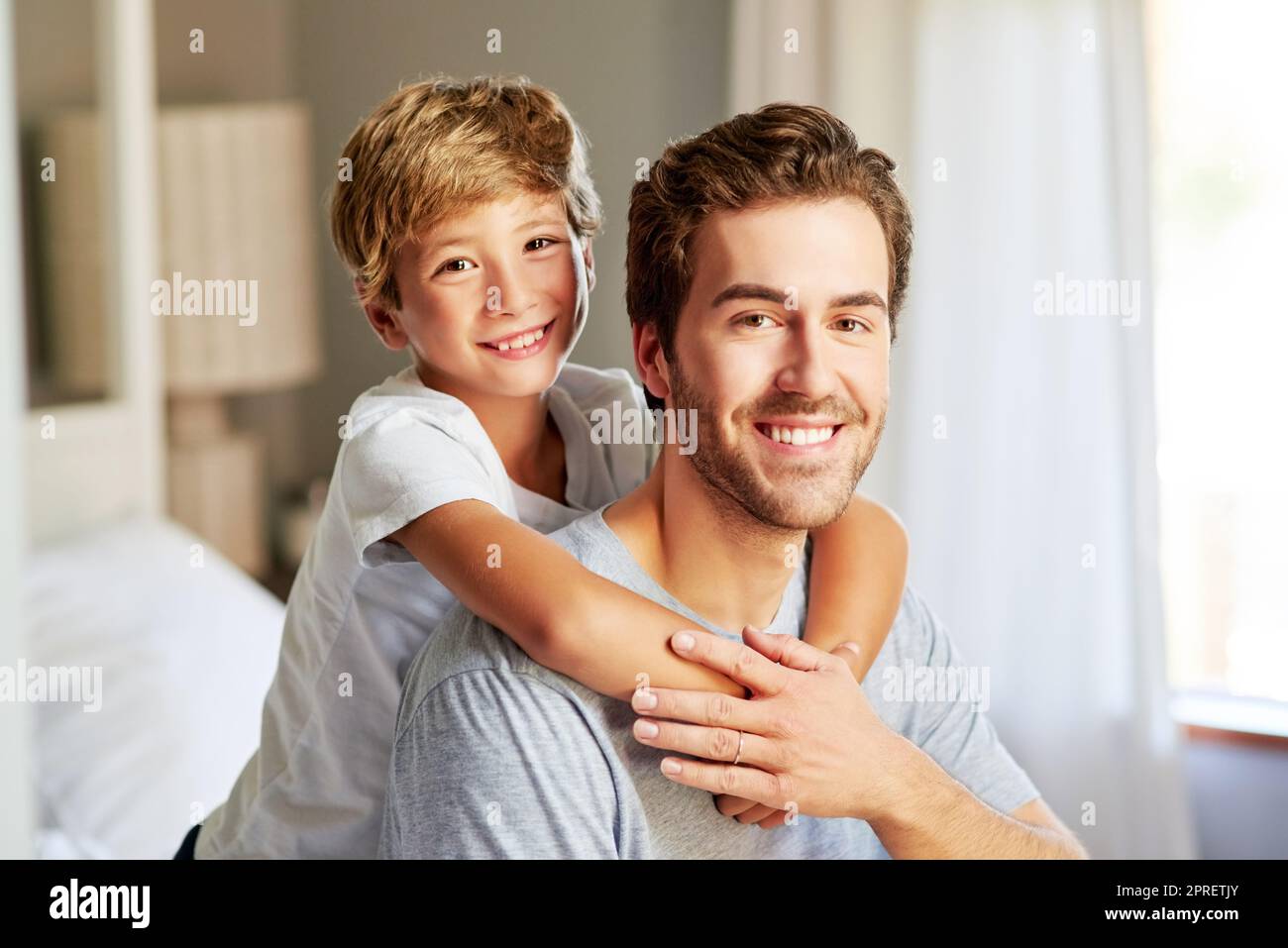 My dad is my best friend. Portrait of a cheerful young boy holding and leaning on his fathers back at home during the day. Stock Photo