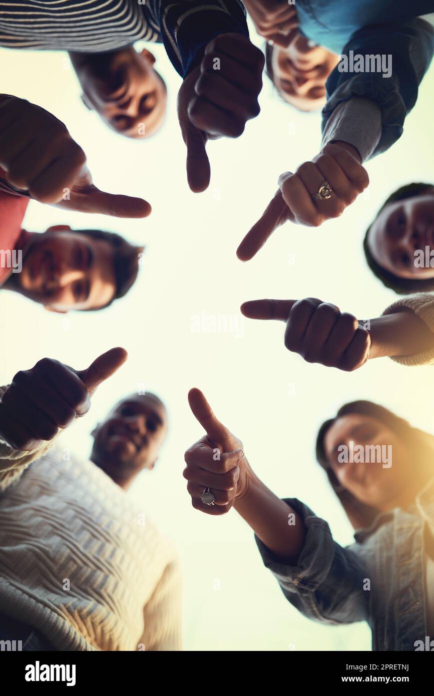 Well back you up. Low angle shot of a group of students giving thumbs up together. Stock Photo