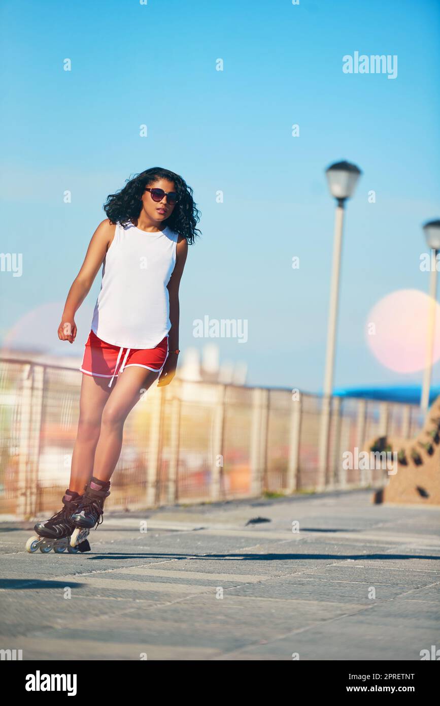 Why walk when you can skate. an attractive young woman rollerblading on a boardwalk. Stock Photo