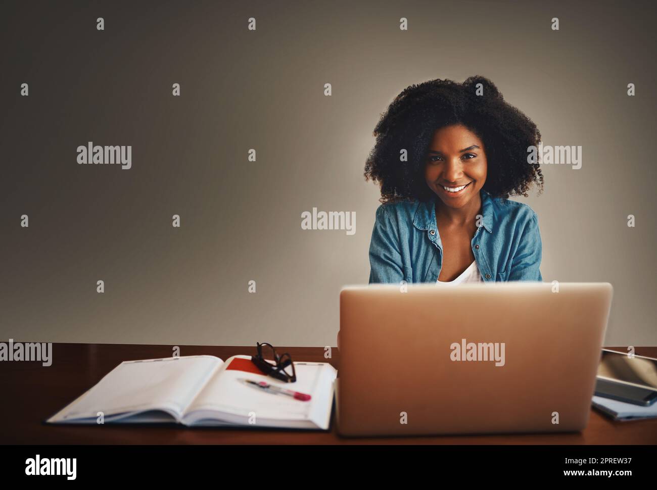 Im proof that anyone can start a successful home business. Studio portrait of an attractive young woman working on a laptop against a dark background. Stock Photo