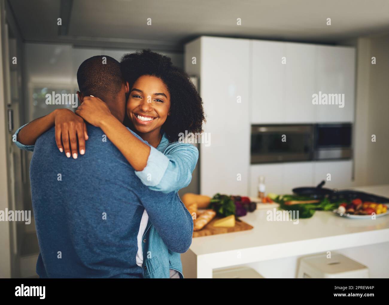 I love having you around. Portrait of a cheerful young couple holding each other and sharing a tender moment in the kitchen at home during the day. Stock Photo