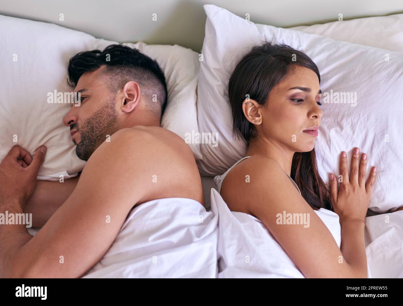 Turning their back to each other and their problems. a young married couple angry at each other in their bed at home. Stock Photo