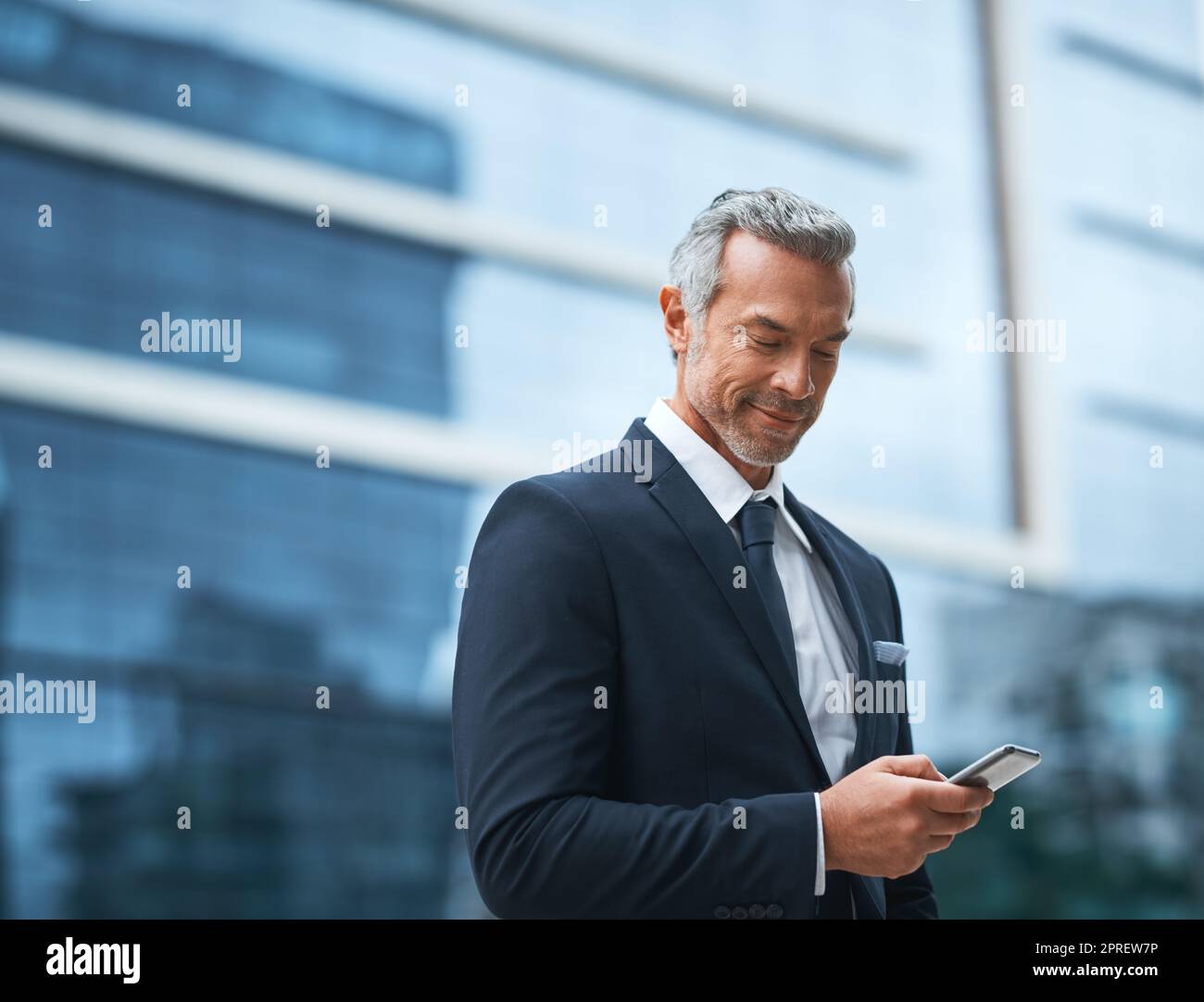 Always working, being a boss didnt come easy. a handsome mature businessman in corporate attire using a cellphone outside during the day. Stock Photo
