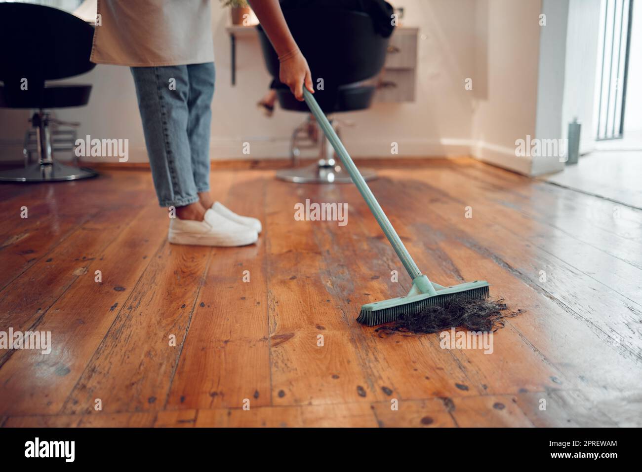 Hairdresser woman, sweeping hair and cleaning salon or