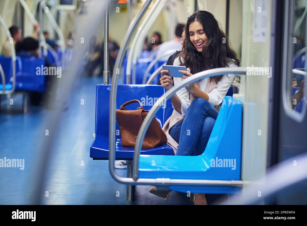 She can binge on shows while commuting. a young attractive woman using a cellphone while commuting with the train. Stock Photo