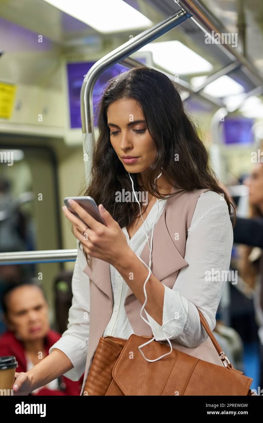What track will be great for this train ride. a young attractive woman using a cellphone while commuting with the train. Stock Photo