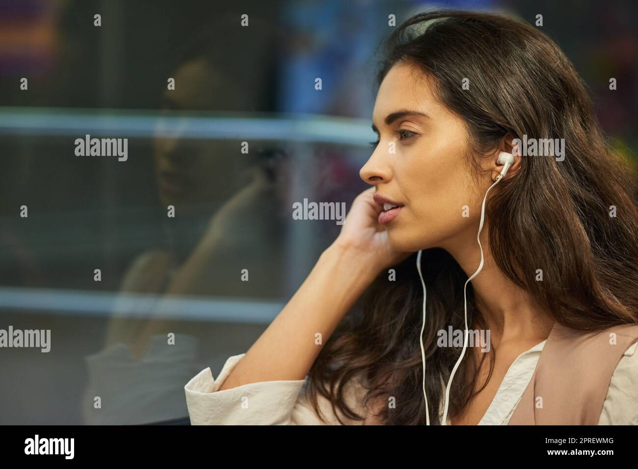 Contemplating on the commute. a young attractive woman listening to music while commuting with the train. Stock Photo