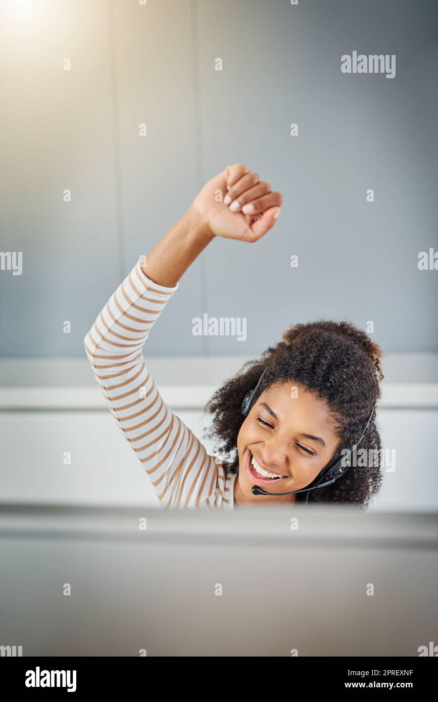 Another deal done. a young woman doing a fist pump while working on a computer at home. Stock Photo