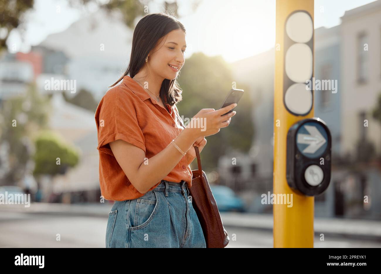 Texting on a phone, browsing social media and waiting for public transport and commuting in the city. Young female tourist enjoying travel and Looking online for places to see and visit on holiday Stock Photo