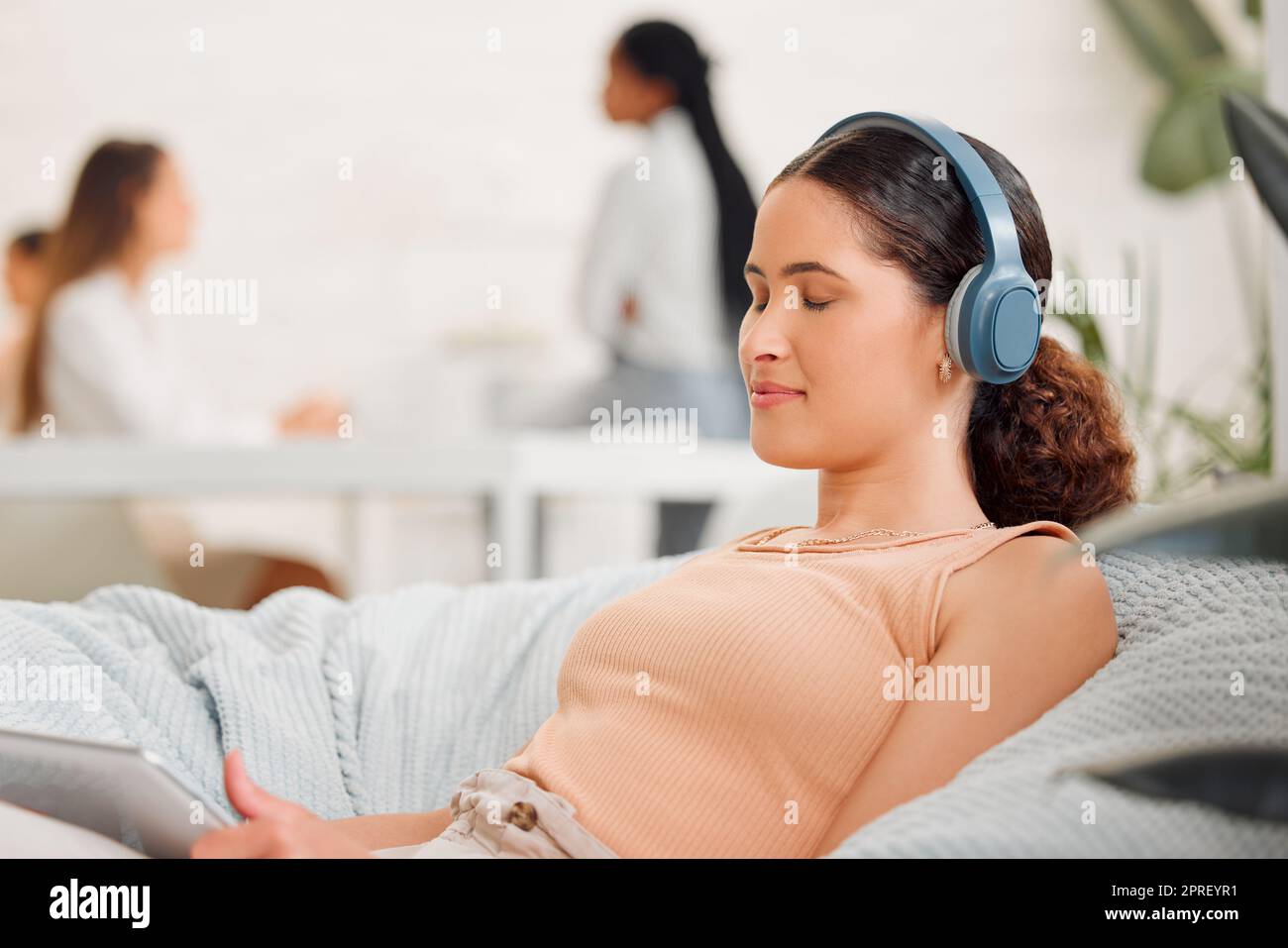 Rest, relaxation and break with a modern and creative design professional listening to music with wireless headphones on a beanbag chair. Young business woman resting in her office for mental health Stock Photo