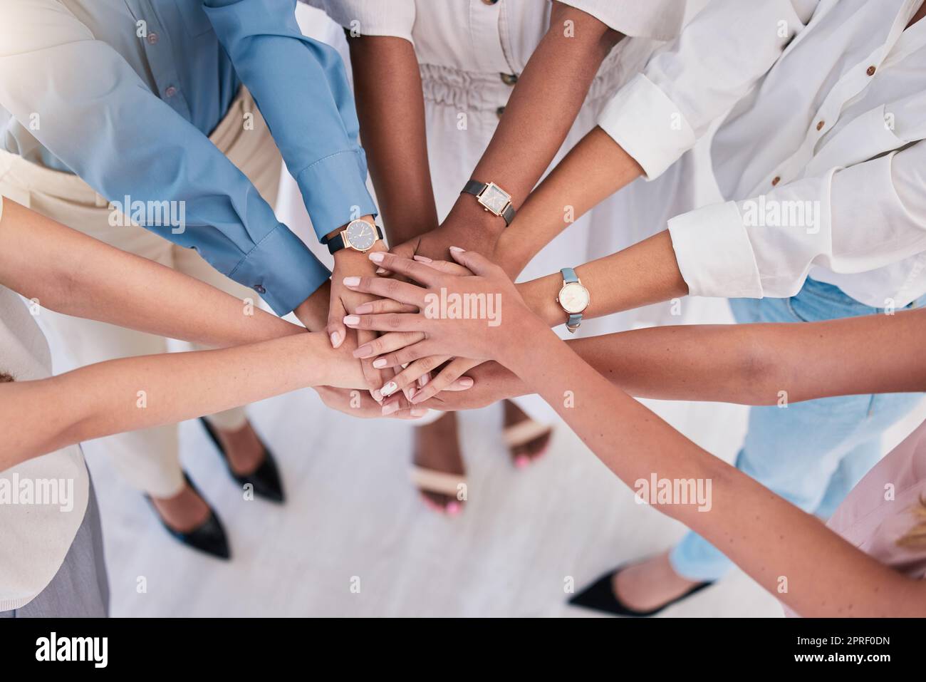 United, successful or ambitious businesspeople hands stacked together in a work office. Business professionals having fun standing with their hands piled for motivation during a meeting from above Stock Photo