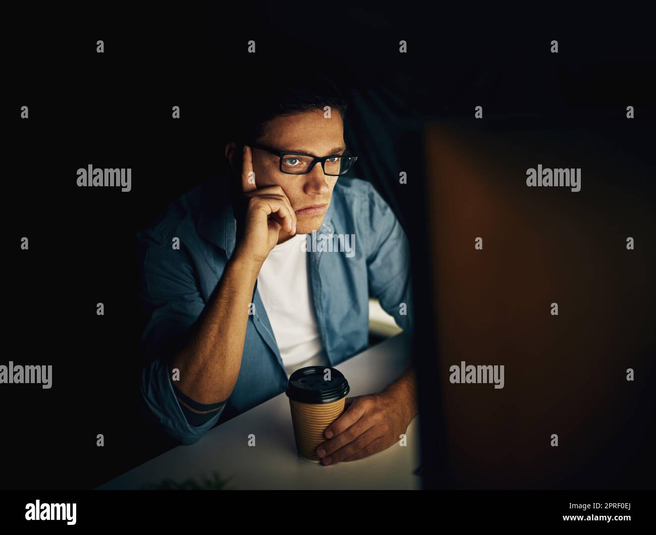 Trying to concentrate but the exhaustion is getting to him. a young man working late in his office. Stock Photo
