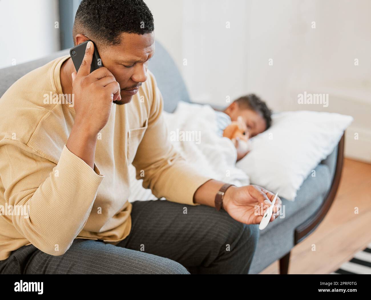 Worried father concerned, caring for sick son calling a doctor and taking temperature check of his sleeping kid at home. Parent consulting with professional and taking care of child with fever Stock Photo
