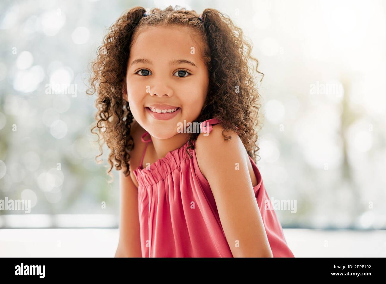 Cute, adorable and sweet young girl with a happy and healthy childhood growing up at home. Portrait of an innocent young female child with a bright smile and relaxing in the house Stock Photo
