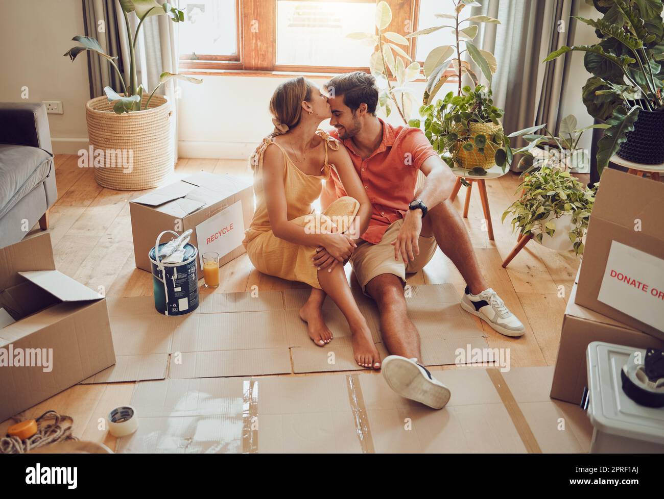 New home owners moving into a house showing affectionate, taking a break from painting and remodeling the living room interior design. In love and loving house wife kissing husband after decorating Stock Photo
