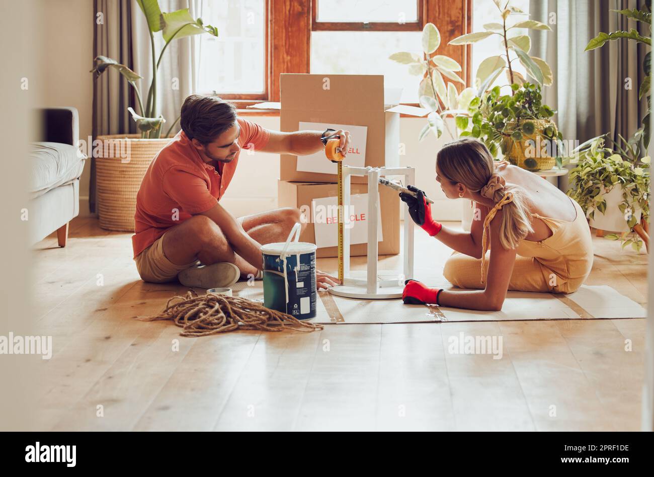 Couple painting wooden table by recycle, donate and thrift furniture for a new home improvement project in new apartment. Creative and DIY man and woman with reusable objects, decorating their house Stock Photo