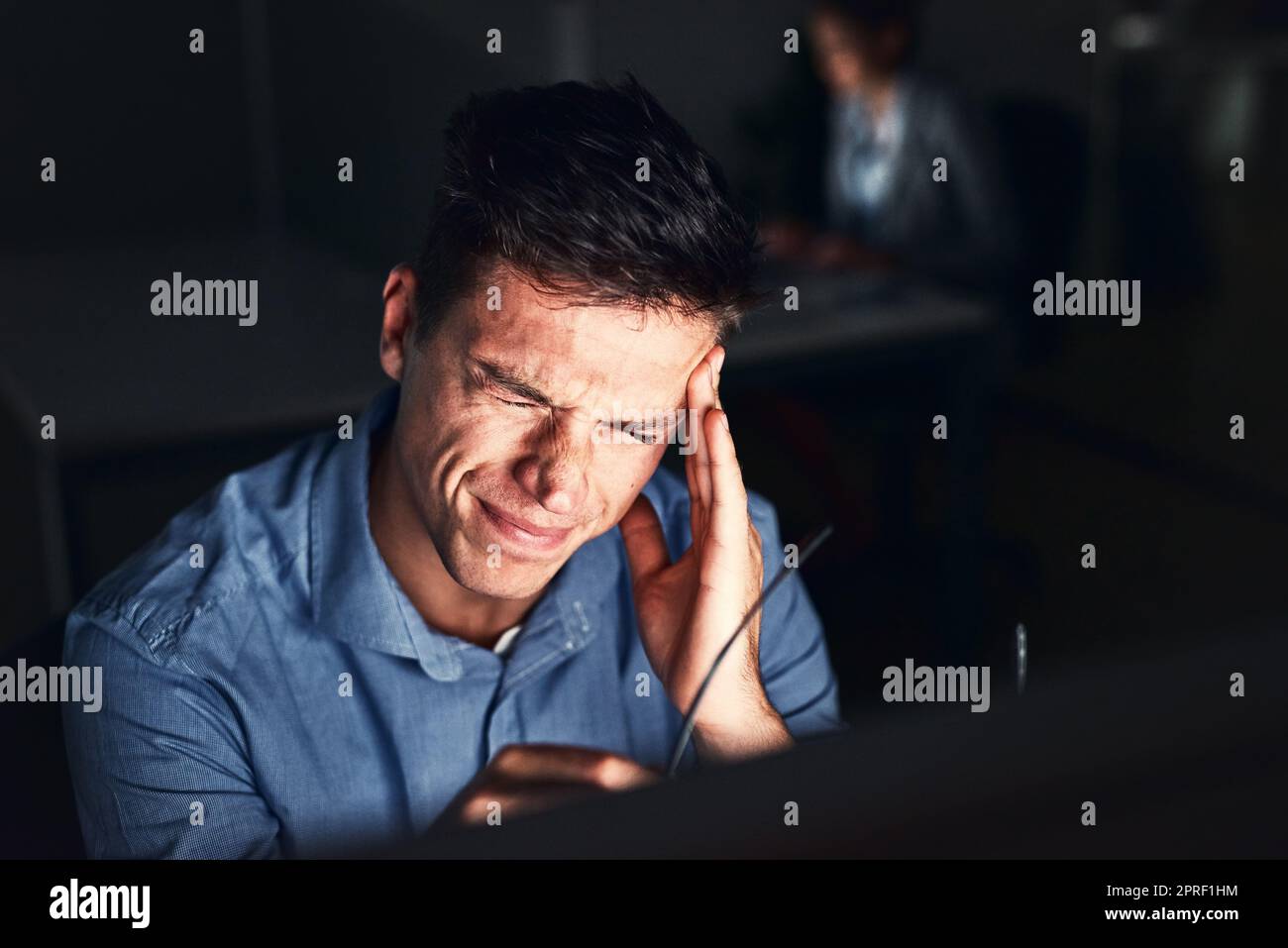 Feeling overworked and the headache is proof. a young attractive businessman working late in the office. Stock Photo