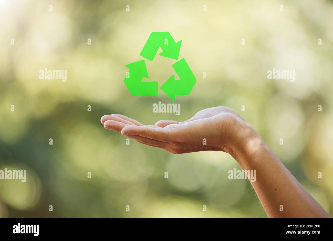 Hand, closeup recycle sign isolated with bokeh effect background. Zero waste, ecology and environmental symbol for sustainable living. Clean and eco friendly habits to protect and save the earth. Stock Photo
