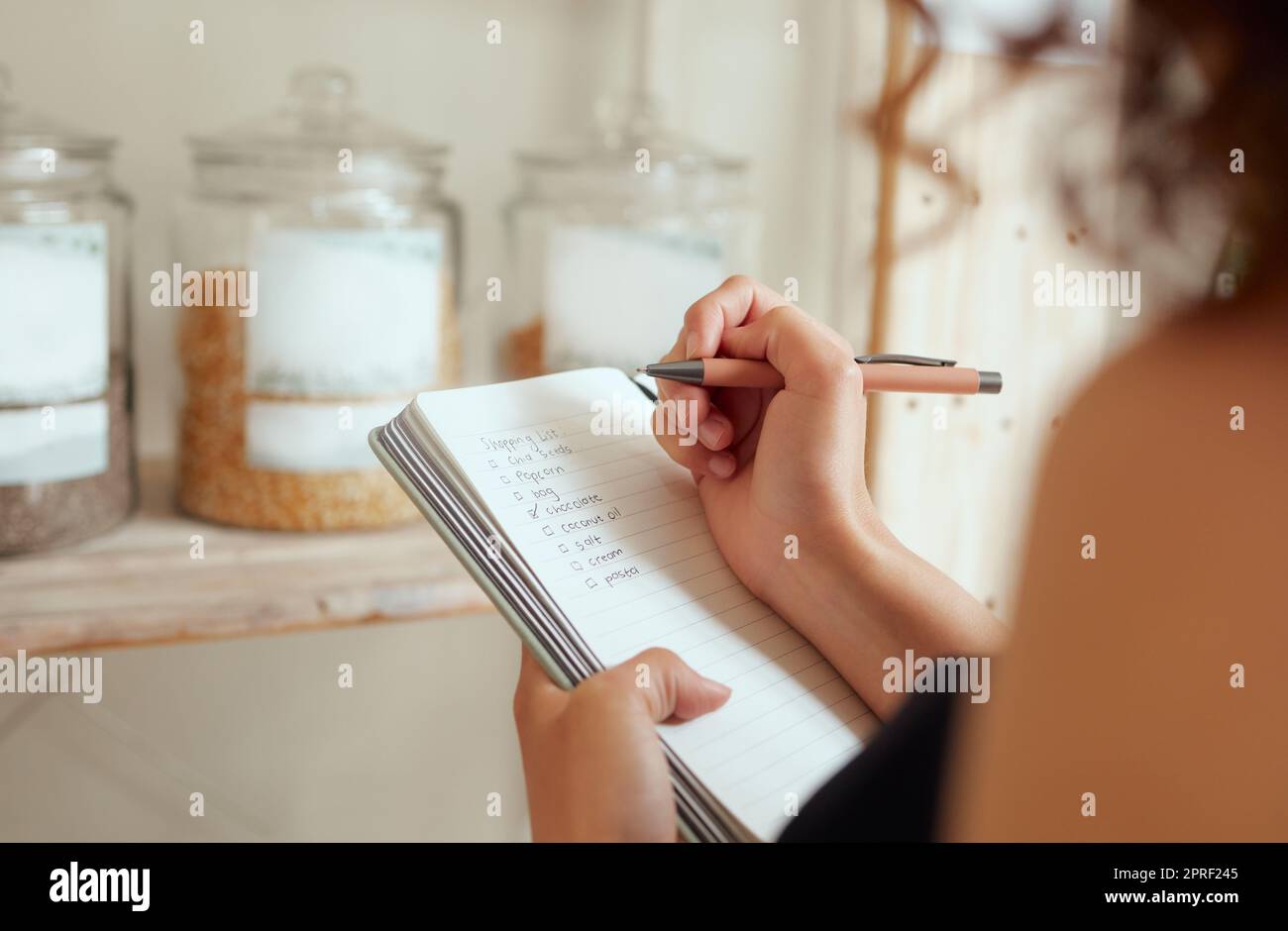 Budget planning, making shopping list and managing household expenses to save money. Financial accountability at home. Woman making shopping list for groceries on a notebook to plan a meal for dinner Stock Photo