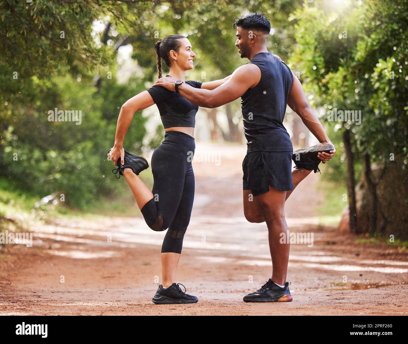 Young fit couple exercising outdoors together, bonding while stretching and preparing for a cardio workout. Athletic girlfriend and boyfriend being affectionate while training and staying healthy Stock Photo