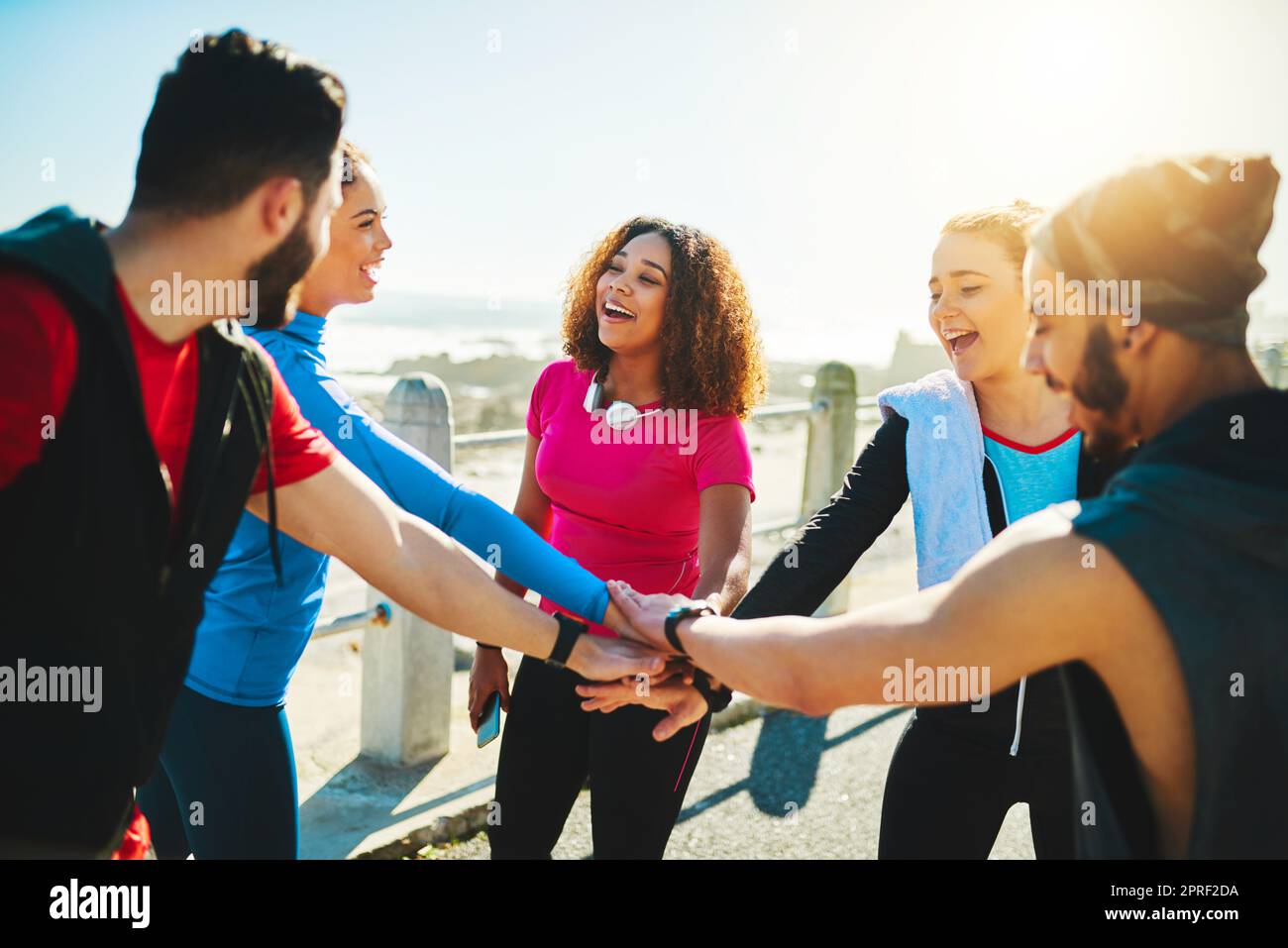 Who will be first today. a group of young cheerful friends forming a huddle before a fitness exercise outside during the day. Stock Photo