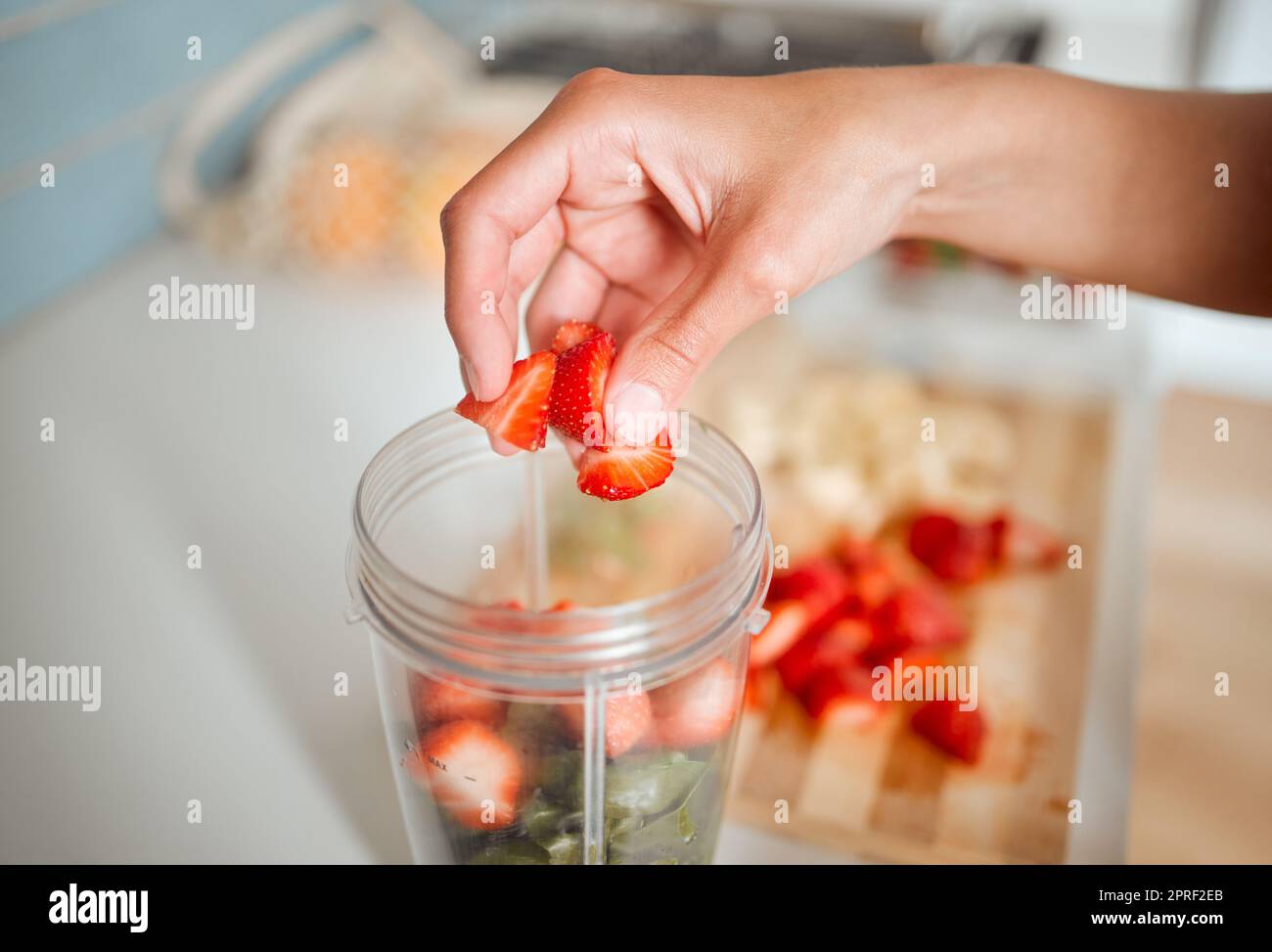 Healthy, diet and fruits while preparing a smoothie or shake in a blender at home. Making a fresh homemade organic drink with strawberries to cleanse and provide energy for vitality and health Stock Photo