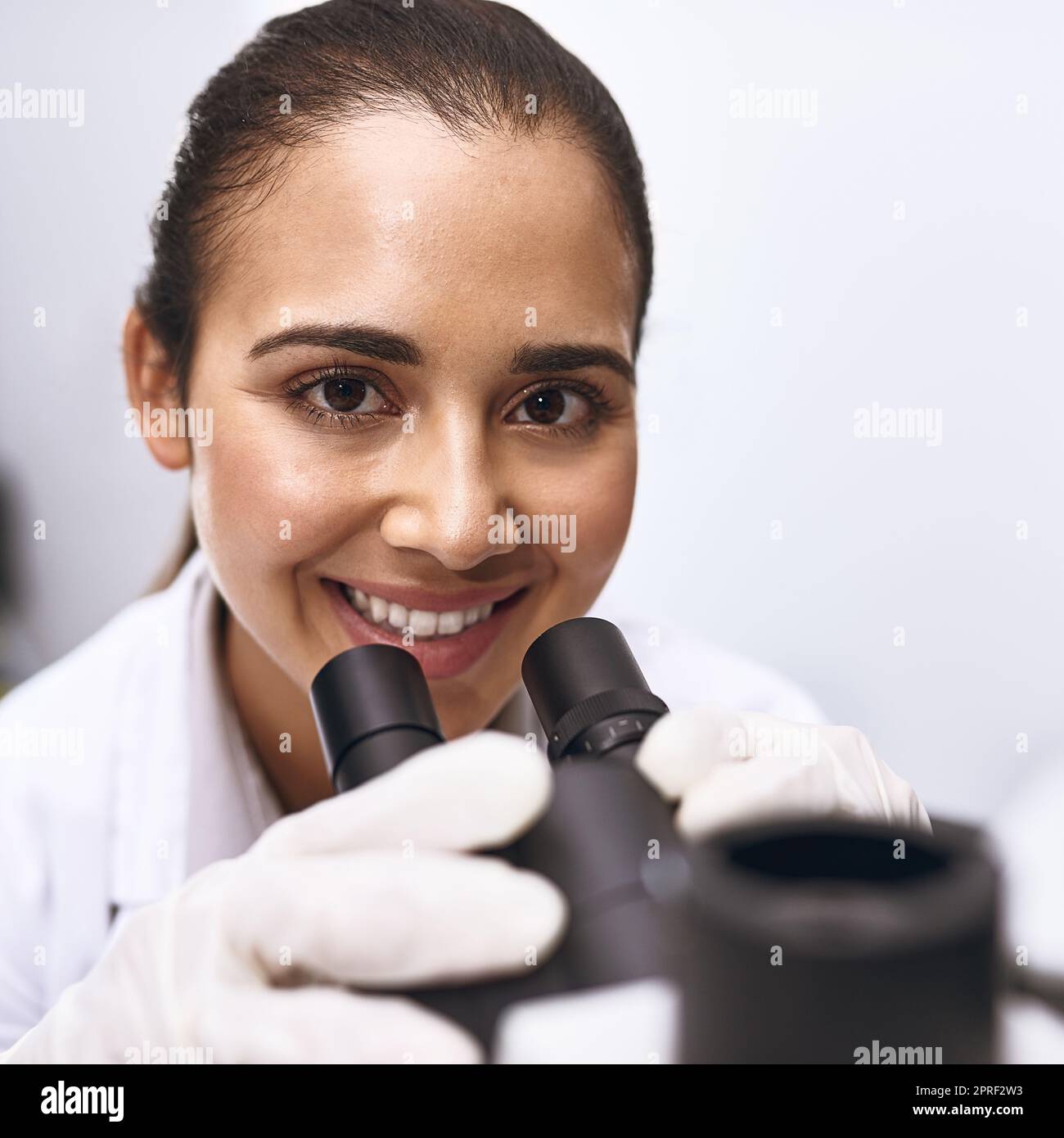 Theres always so much to discover. Portrait of a young scientist using a microscope in a lab. Stock Photo