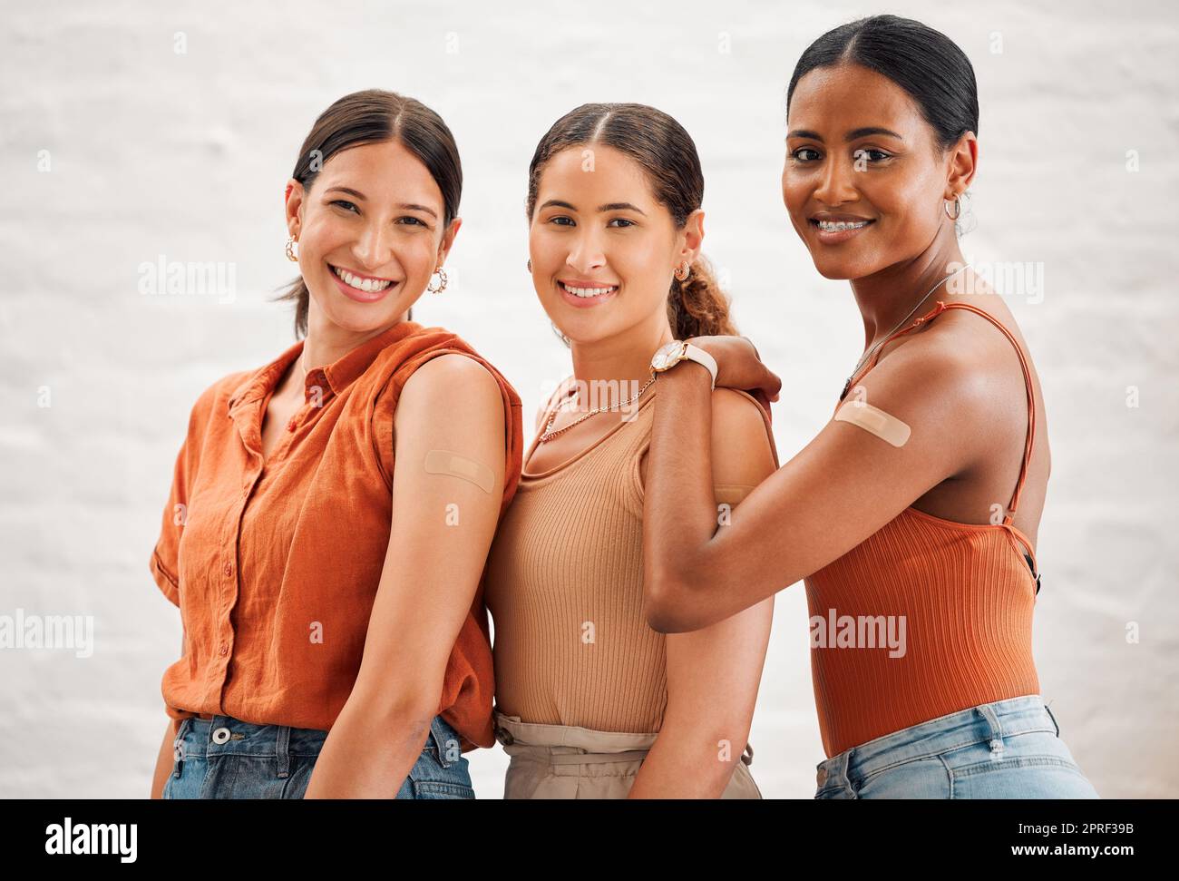 Covid vaccination or flu shot inside of girl friends, female friendship and teenagers smiling. Portrait of a happy and diverse friend group standing and practicing good health habits together Stock Photo
