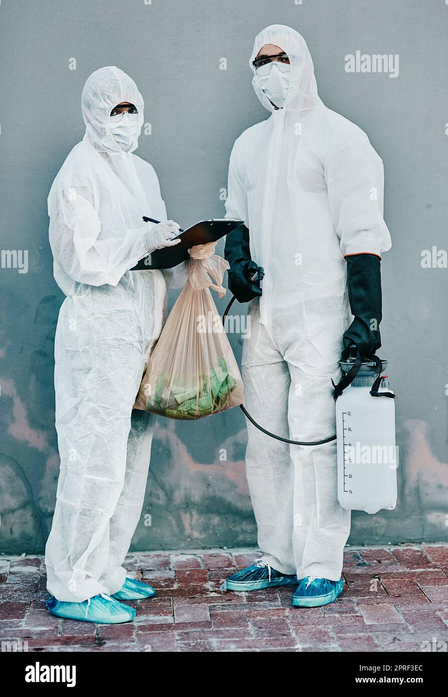 Scientists disinfect isolated and dangerous area. Medical staff protect themselves with sterile equipment. Healthcare workers clean while wearing safety uniform to stop the spread of a virus. Stock Photo