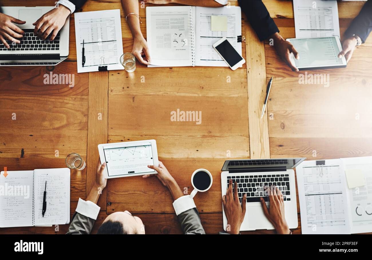 Above desk of accounting colleagues having a meeting and analyzing big data in office. Businesspeople planning with papers and multiple devices for growth development and innovation with copy space Stock Photo
