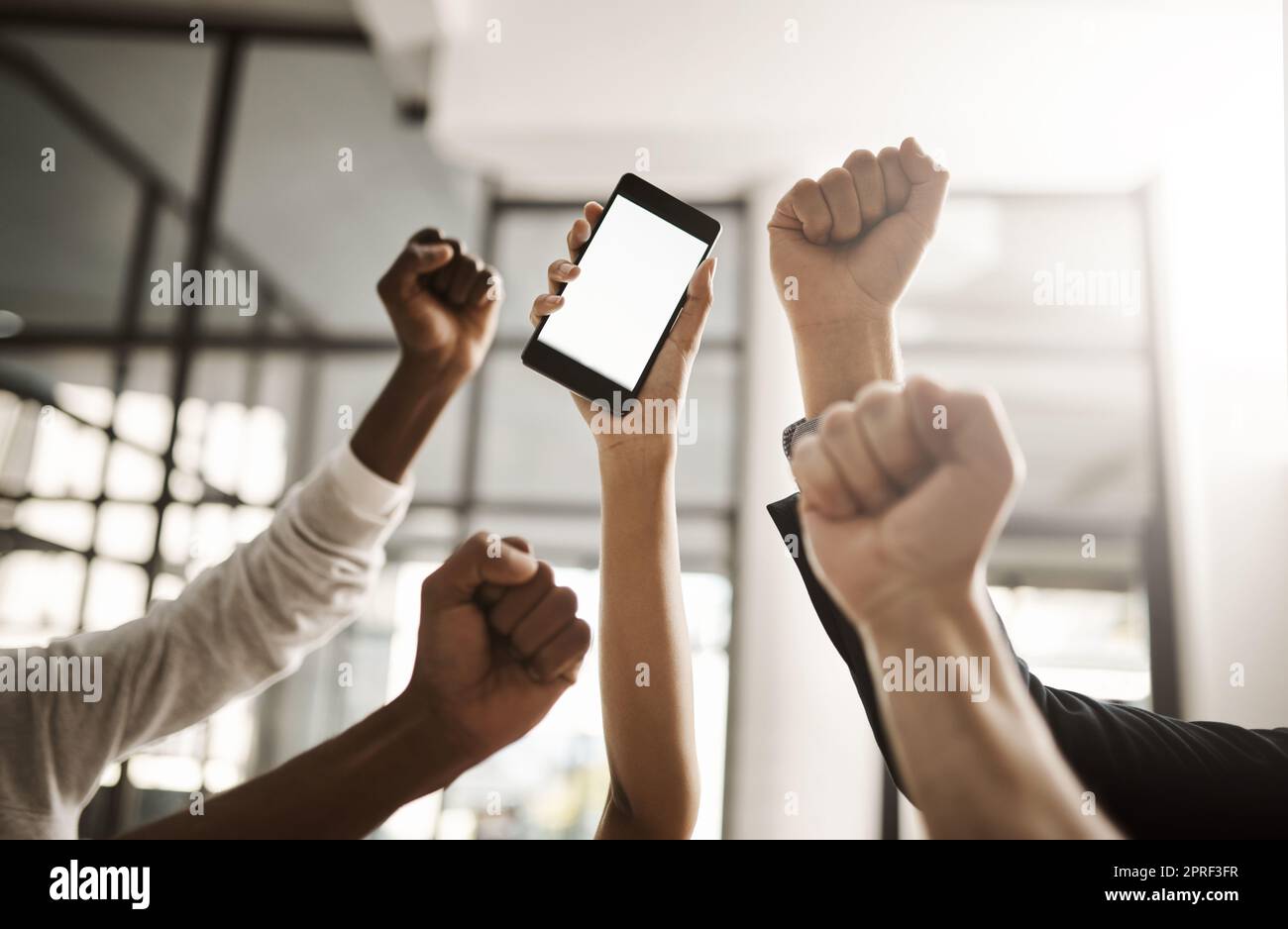 Hands of business people cheering, celebrating good news on a phone with blank screen for copy space. Excited team of office workers showing power fist gesture for success, victory and winning Stock Photo