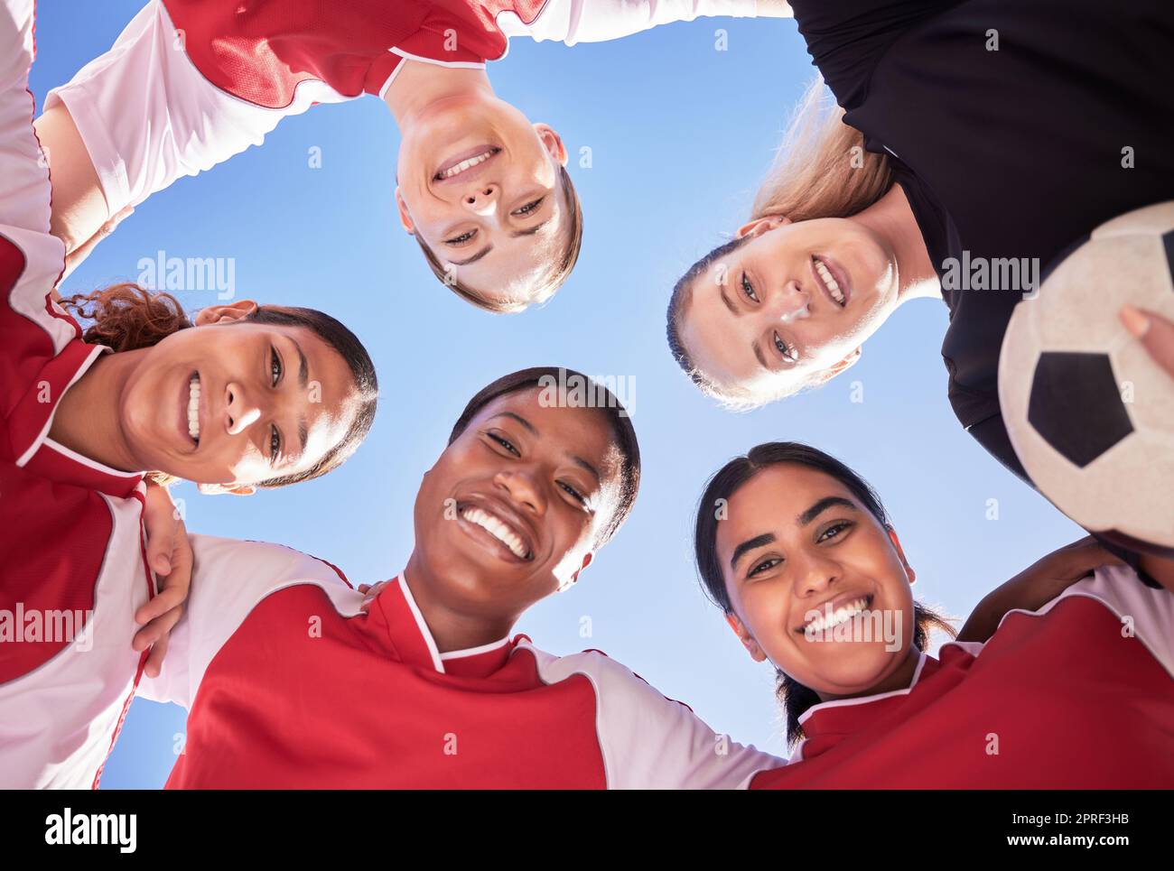 A soccer team of females only in a huddle during a match happy about winning the competition. Low angle portrait of a womens football squad standing in a circle in unity and support as game strategy Stock Photo