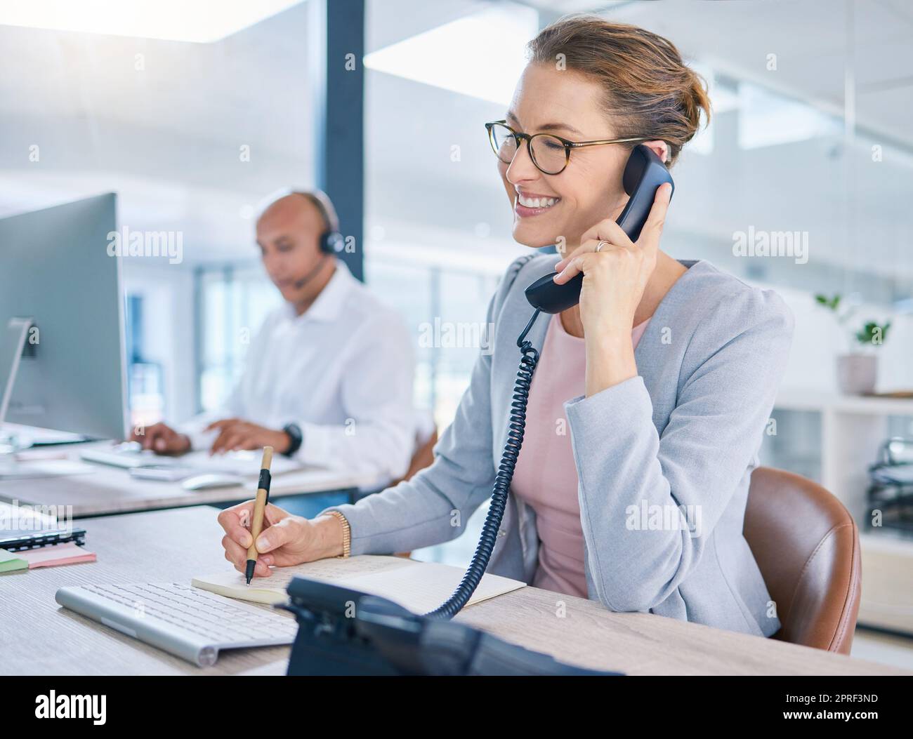 Call center operator, marketing agent and sales consultant networking, talking and consulting on telephone. Friendly secretary, business woman and support helpdesk writing notes for customer service Stock Photo
