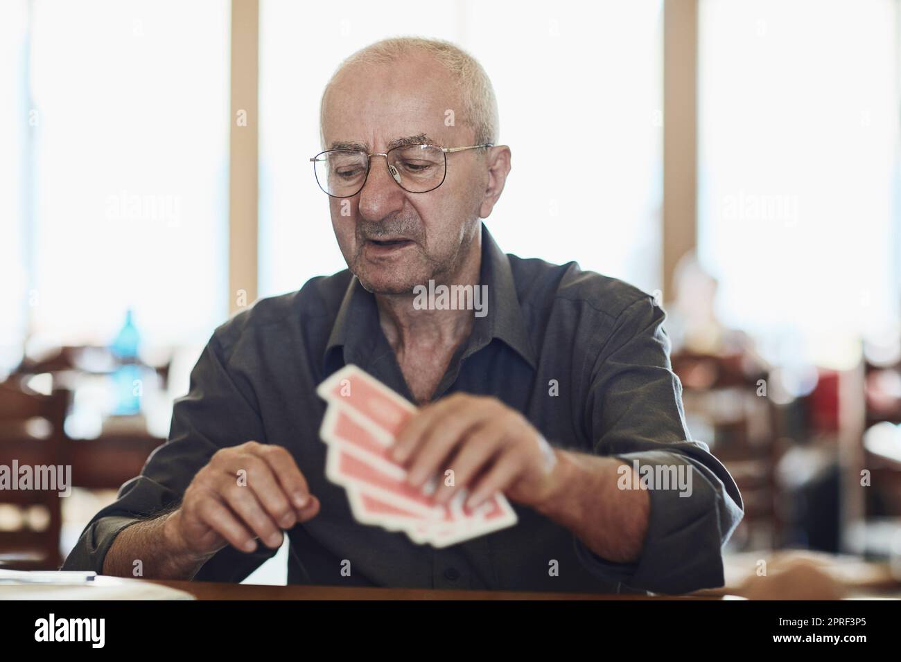 Thinking about his next move. seniors playing poker in their retirement home. Stock Photo