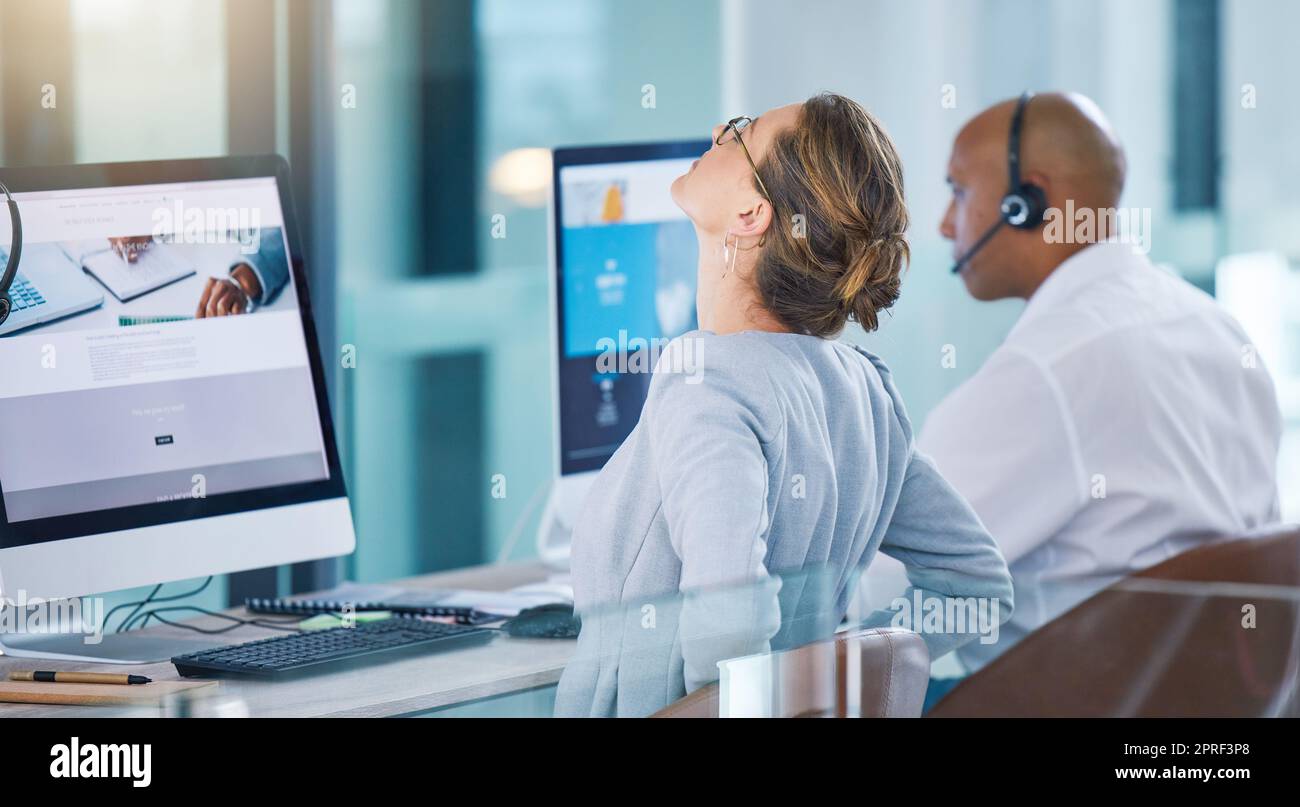 Stressed, overworked or stretching sales consultant, telemarketing operator or call center agent working on website. Tired customer support employee suffering from bad posture at contact us helpdesk Stock Photo