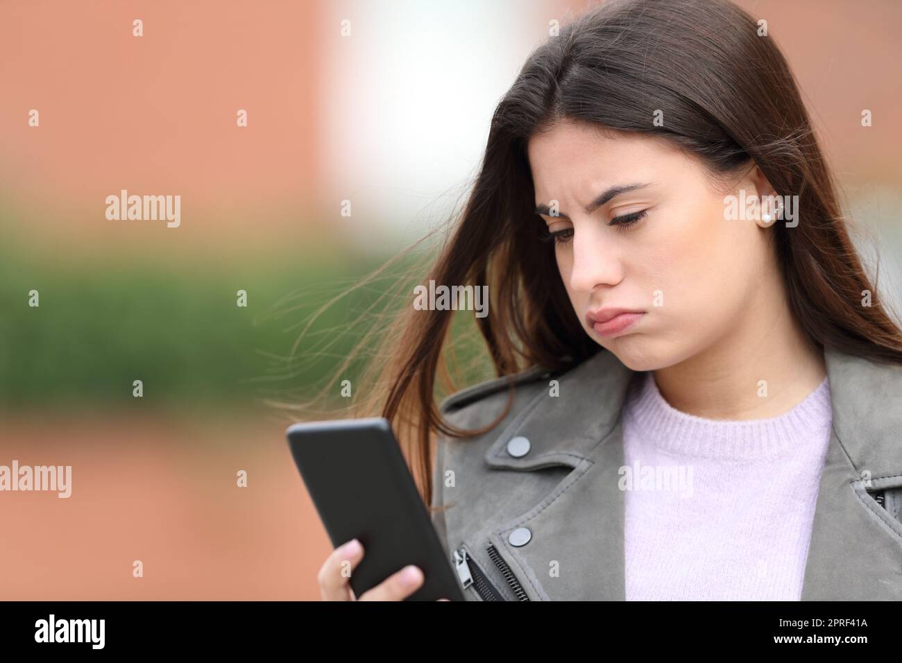 Bored teen checks smart phone in the street Stock Photo