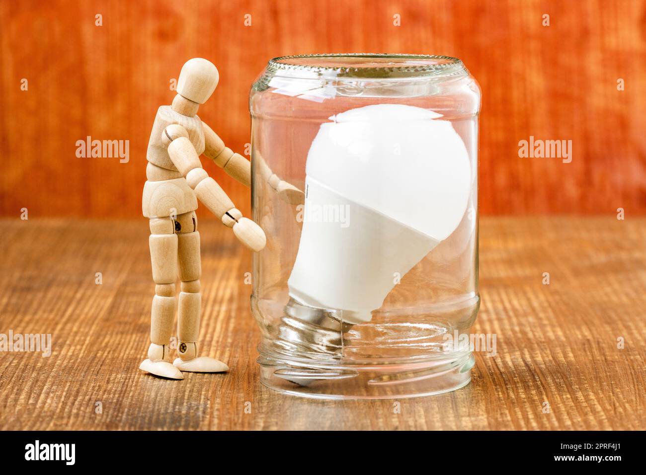 Dummy standing next to light bulb inside glass jar Stock Photo