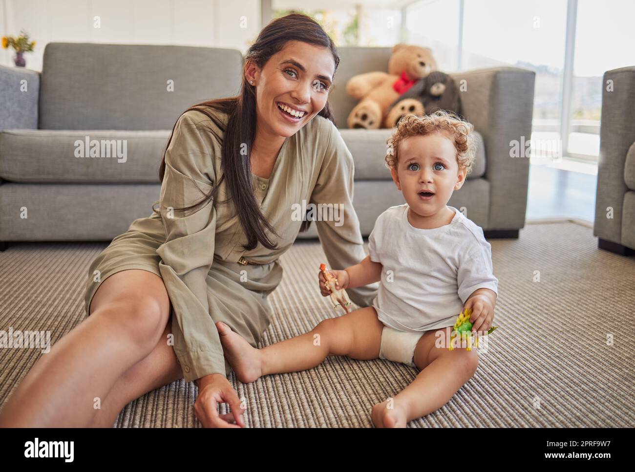 Mother, baby and smile in living room playing together on carpet in home, for fun and learning with toys. Child, mom and floor with dinosaurs figure, Stock Photo