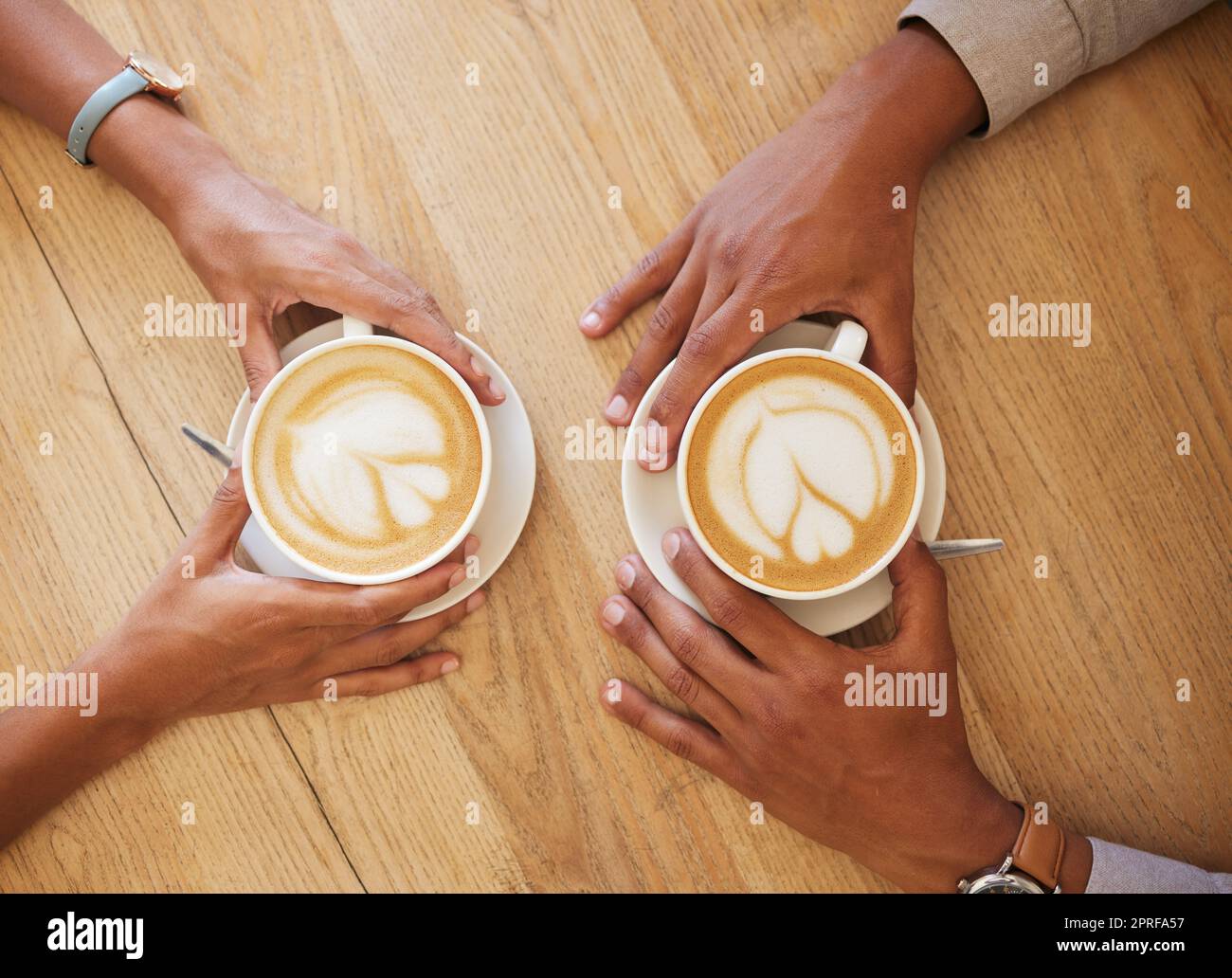 Creative latte art, cappuccino and coffee drink in cafe with couple and friends enjoying cup of java with milk froth together. Closeup of people hands from above meeting and drinking in restaurant Stock Photo
