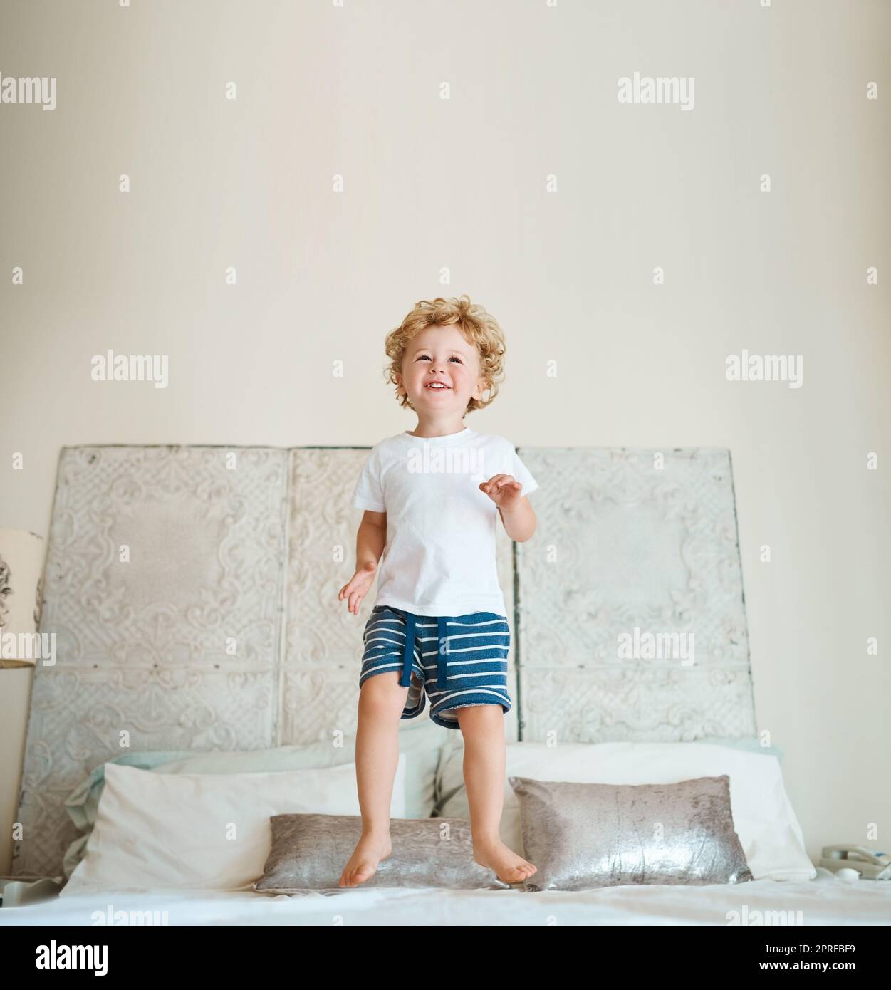 Such joy just jumping on a bed brings him. an adorable little boy jumping on the bed at home. Stock Photo
