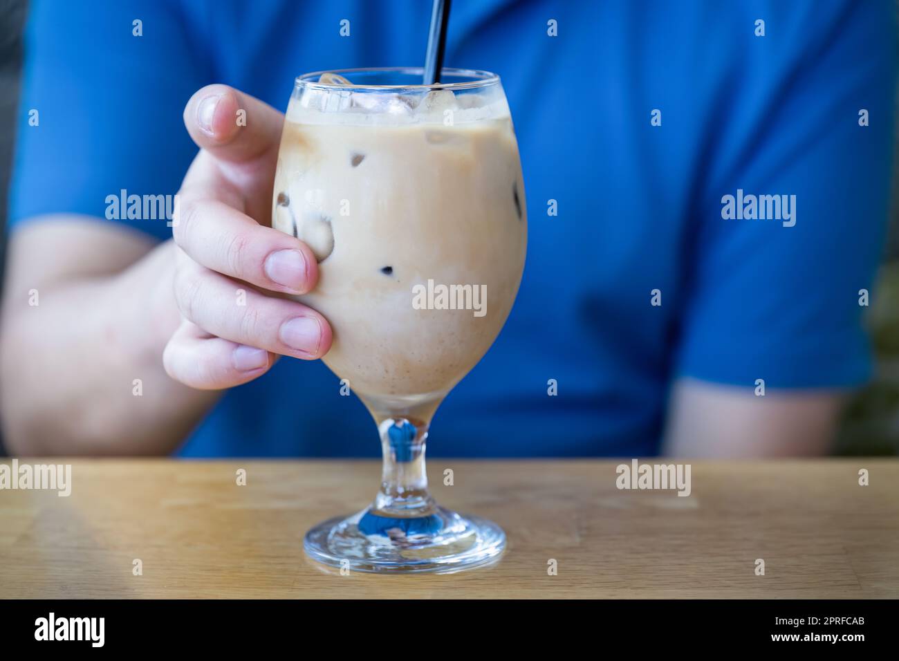 Male hand holding a glass of iced latte coffee. Cold brew refreshment ...