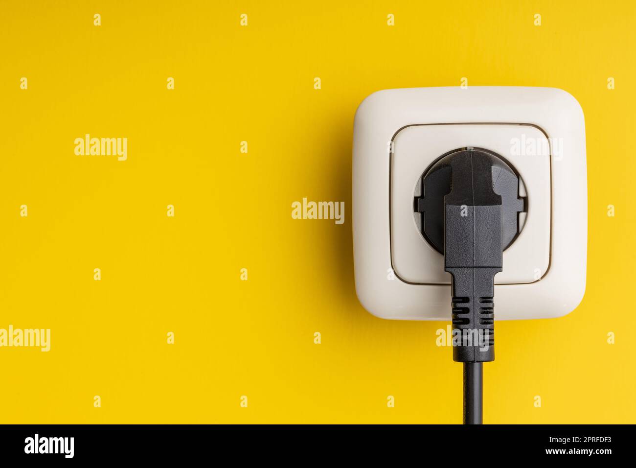 Electric plug and wall socket on yellow wall. Stock Photo