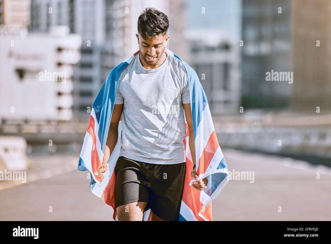 Fitness, training and workout with a sports man in a british flag running a marathon in the city. Health, exercise and wellness with an olympic athlete or runner exercising for cardio and endurance Stock Photo