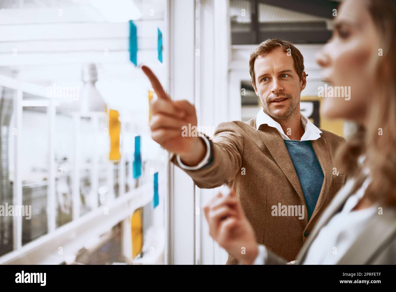 We need to deal with this. two businesspeople working on a glass wipe board in their office. Stock Photo