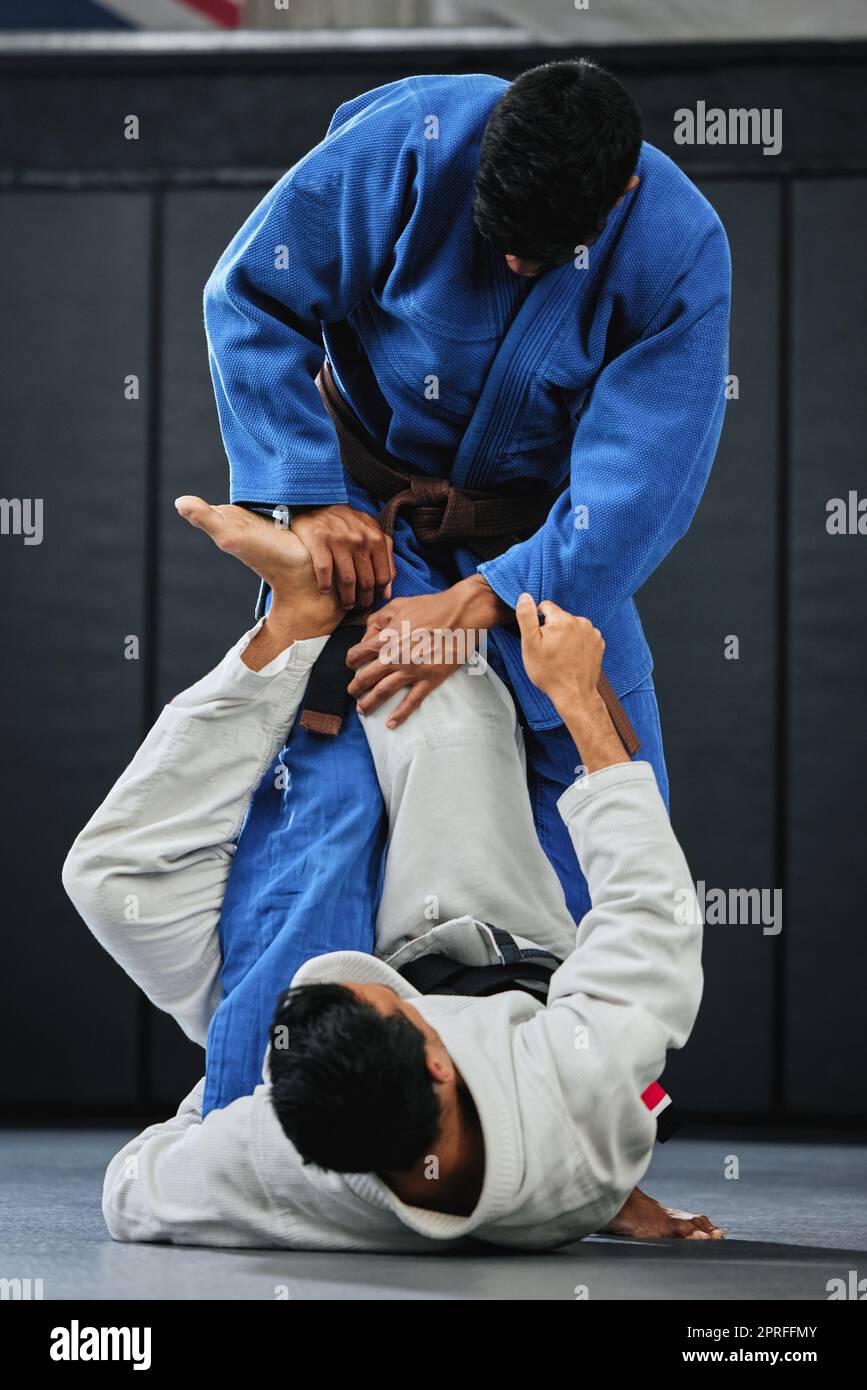 Karate, fitness and exercise of a student training with a coach and learning in a contact sport. Man with personal trainer in martial arts sports fight for safety, wellness and health in a gym. Stock Photo