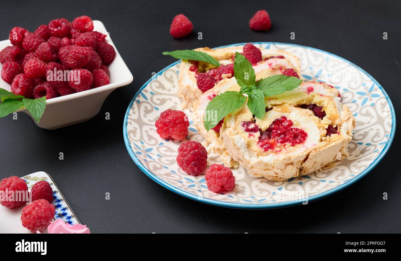 Baked meringue roll with cream and fresh red raspberry Stock Photo - Alamy